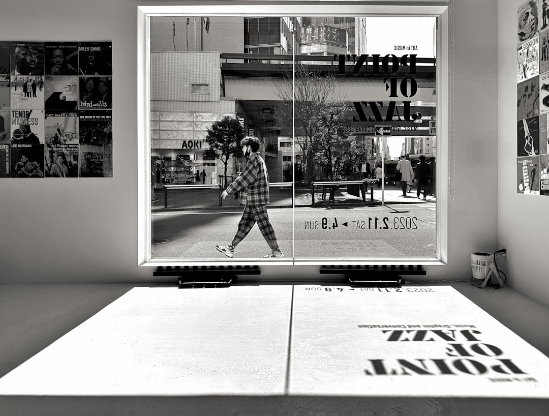 a-black-and-white-photo-of-a-man-walking-past-a-window-kbu3x8u3-8q